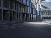 the empty road is lined with tall buildings near some glass doors by the window sills