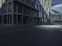 the empty road is lined with tall buildings near some glass doors by the window sills