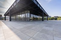 an empty concrete floor is seen with lots of glass walls and steel frame around the structure