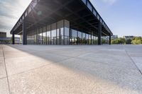 an empty concrete floor is seen with lots of glass walls and steel frame around the structure