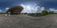 a fish eye lens of an art museum and sky background with white clouds, trees, and rocks