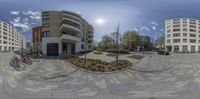 the view looking up at a building from inside of a 360 camera lens with some bicycles parked in front