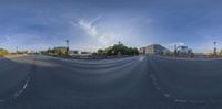 a wide street with empty street lights and buildings in the background of this 360 - effect photograph