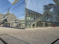 a large glass building with stairs leading up to it's sides, near water and buildings