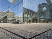 a large glass building with stairs leading up to it's sides, near water and buildings