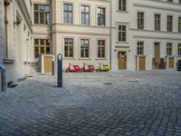 an empty parking lot with plants in the ground and on the side of the building, there is an enclosed area and windows