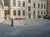 an empty parking lot with plants in the ground and on the side of the building, there is an enclosed area and windows