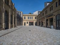 the sidewalk is paved with stones and has a bench in front of it, with no people inside