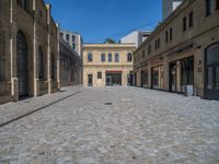 the sidewalk is paved with stones and has a bench in front of it, with no people inside