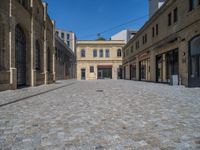 the sidewalk is paved with stones and has a bench in front of it, with no people inside