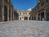 the sidewalk is paved with stones and has a bench in front of it, with no people inside