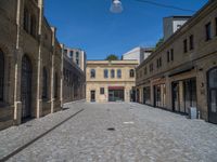 the sidewalk is paved with stones and has a bench in front of it, with no people inside