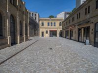 the sidewalk is paved with stones and has a bench in front of it, with no people inside