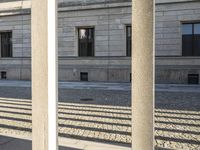 three columns and benches sitting outside of the building with windows to both sides of it