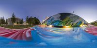 an outdoor water park features a water feature, like the rainbow wave pool, at night