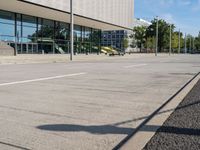 a person skateboarding down an empty sidewalk in front of a building with glass walls