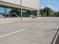 a person skateboarding down an empty sidewalk in front of a building with glass walls