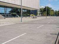 a person skateboarding down an empty sidewalk in front of a building with glass walls