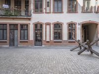 a metal piece in the middle of an outdoor courtyard by a brick building and door