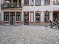 a metal piece in the middle of an outdoor courtyard by a brick building and door