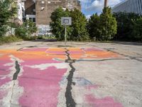 painted graffiti marks in an empty parking lot with a basketball court on the ground and a street sign to the left