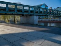 a skateboarder riding on a cement ramp next to a city street under a bridge