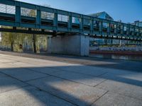 a skateboarder riding on a cement ramp next to a city street under a bridge