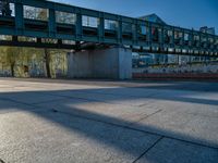 a skateboarder riding on a cement ramp next to a city street under a bridge