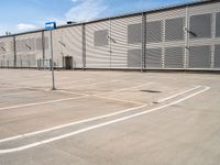 an empty parking lot with a building in the background, which has blue signs in white and blue