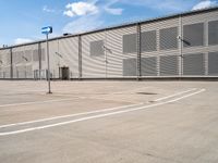 an empty parking lot with a building in the background, which has blue signs in white and blue