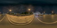 the view of an empty street at night in a city with traffic moving in front of it