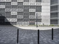 a couple walking next to each other on top of brick walkways and a cement building with geometric designs