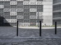 a couple walking next to each other on top of brick walkways and a cement building with geometric designs