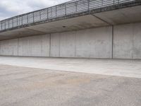 a man is riding his skateboard on the sidewalk underneath a bridge on the waterfront