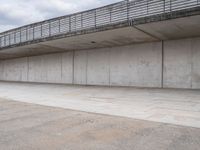 a man is riding his skateboard on the sidewalk underneath a bridge on the waterfront