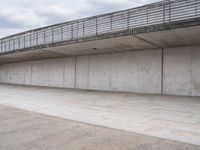 a man is riding his skateboard on the sidewalk underneath a bridge on the waterfront