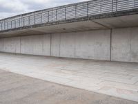 a man is riding his skateboard on the sidewalk underneath a bridge on the waterfront