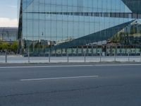 a street next to a modern glass building with a curved exterior and railings on the sides