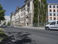 cars driving on the street next to a building with two stories and trees on each side