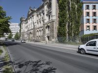 cars driving on the street next to a building with two stories and trees on each side