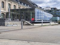 red suitcases are on the sidewalk in front of a glass building with stairs and other stairs