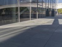 a man riding a skateboard next to glass windows on the sidewalk outside a building