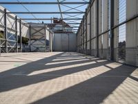 a walkway through an unfinished building with windows and metal construction on either side of it