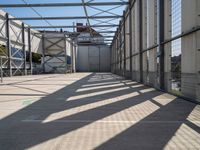 a walkway through an unfinished building with windows and metal construction on either side of it