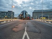 empty street with some buildings and a light on it at dusk, with the road turned red