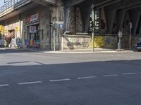 an empty street in front of an overpass with graffiti on it and cars driving down the street