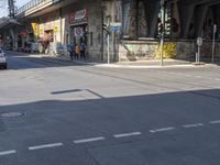 an empty street in front of an overpass with graffiti on it and cars driving down the street