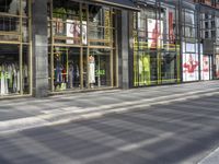 a woman riding a bike past a building with some windows and signs on the side of it