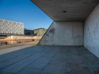 a skateboarder riding on a cement ramp next to a city street under a bridge