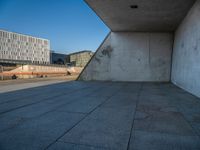 a skateboarder riding on a cement ramp next to a city street under a bridge